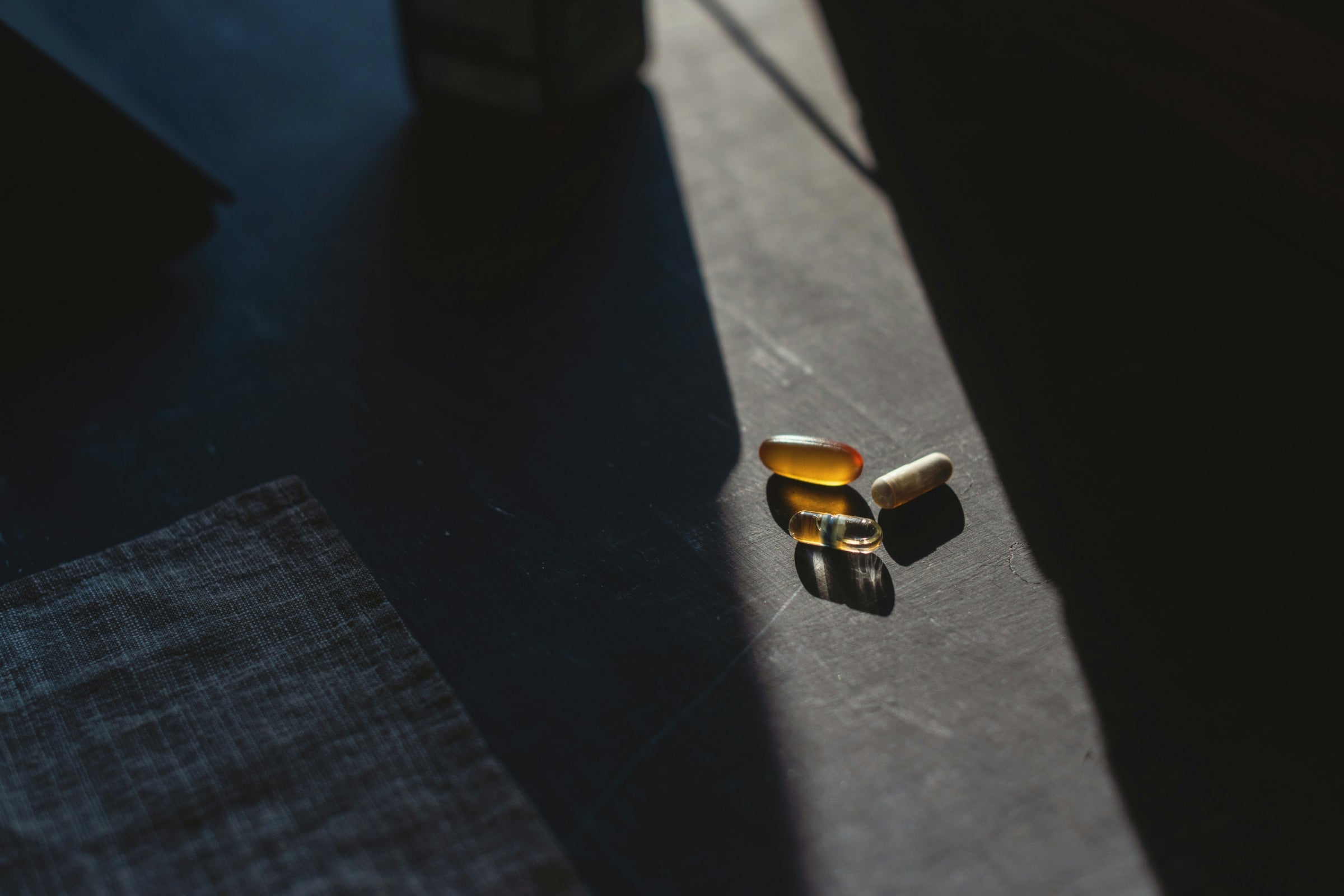 Close-up of supplement pills on a table, representing nicotinamide riboside (NR) impact on liver fat metabolism.