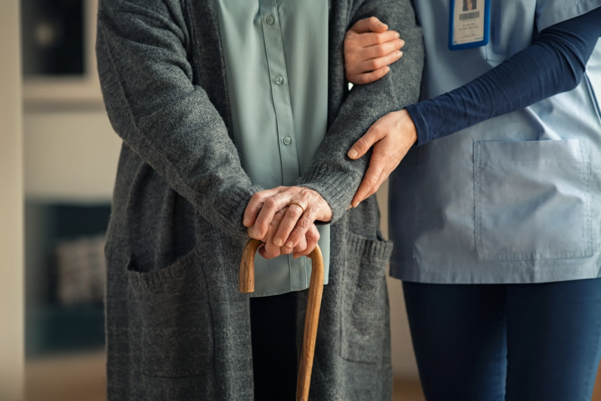 Older adult with aging hands gripping a walking cane, illustrating the link between low NAD+ levels and age-related frailty.